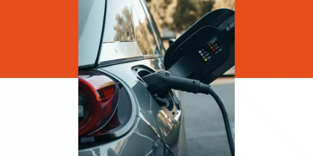 Gros plan sur un véhicule électrique en cours de recharge sur une borne IRVE, avec le câble branché sur le port de charge et l’écran de la borne affichant des indicateurs lumineux.