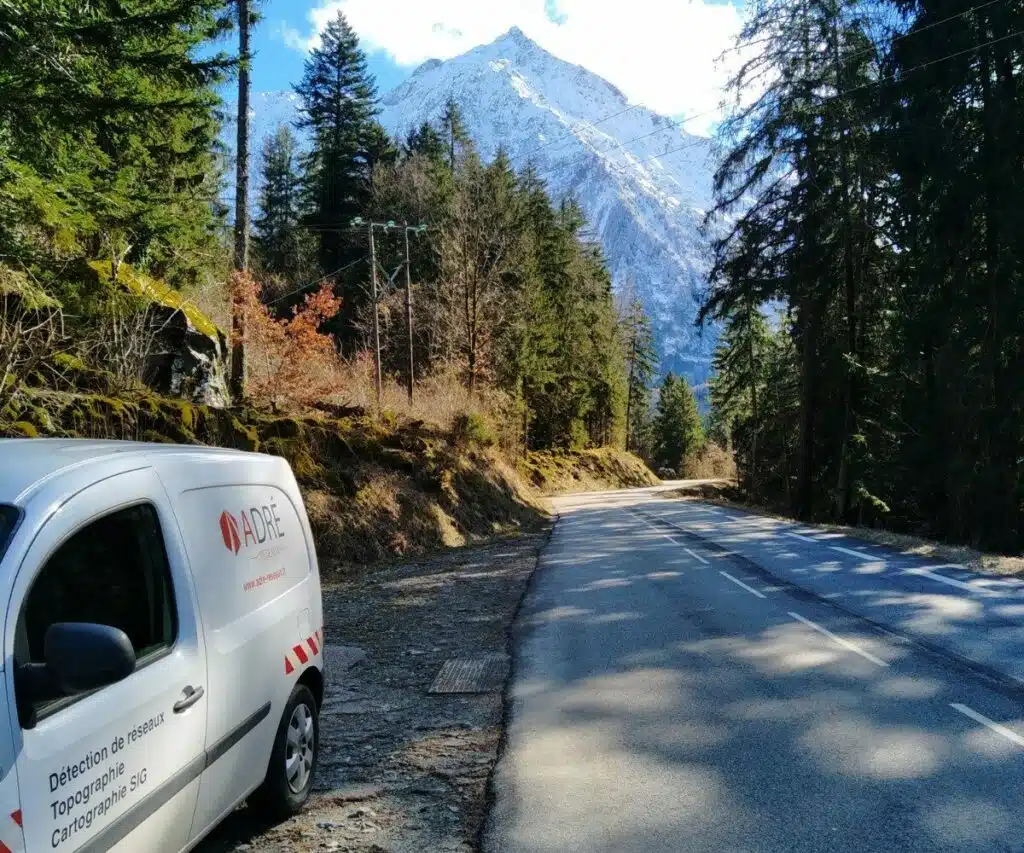 Véhicule ADRÉ Réseaux en intervention pour un relevé topographique en zone de montagne à Vénosc (Isère), sur une route forestière enneigée.